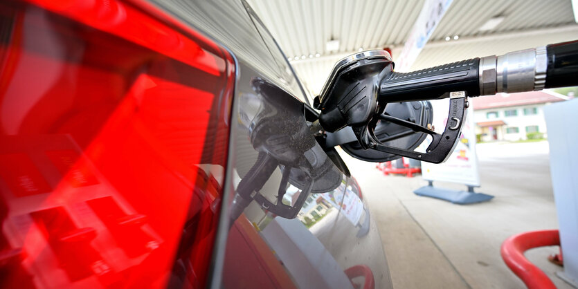 Rote Rückleuchte und Zapfhahn in einem Auto an der Tankstelle