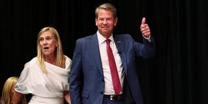 Georgias Gouverneuer Brian Kemp läuft mit seiner Frau auf die Bühne und hält lächelnd den Daumen hoch