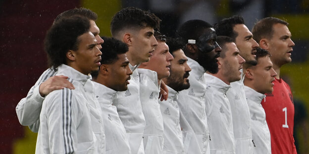Die deutsche Fußball-Nationalmannschaft der Männer, in einer Reihe aufgestellt, manche singen die Nationalhymne mit