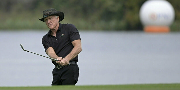 Ein Golfball im Vordergrund. Greg Norman mit Cowboy-Hut im Hintergrund