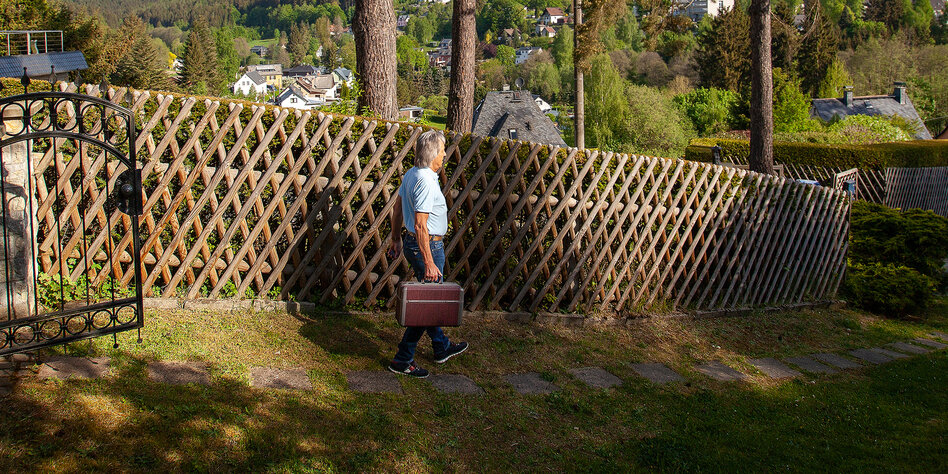Eine Person mit Koffer in der Landschaft.