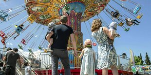 Ein Paar mit zwei Kindern steht vor einem Kettenkarussell