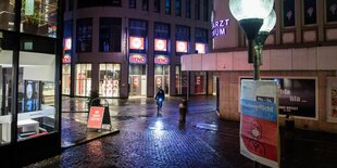 Ein Fahrradfahrer in der nächtlichen Kieler Altstadt. Die Straßen sind gepflastert, die drei sichtbaren Gebäude groß und modern