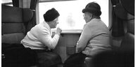 Zwei alte Frauen sitzen im Zugabteil und schauen aus dem Fenster