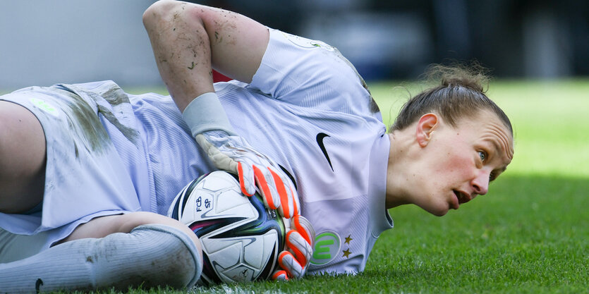 Almuth Schult liegt auf dem Rasen, einen gehaltenen Ball in der Hand