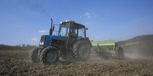 Arbeiter pflügen ein Weizenfeld im Westen der Ukraine