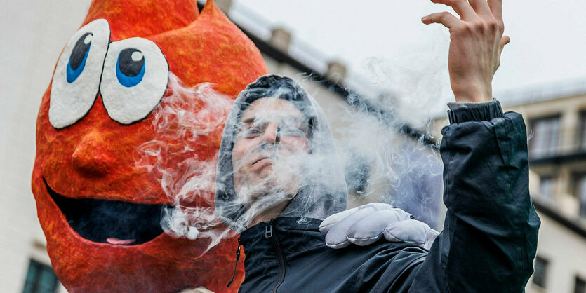 Ein junger Mann auf einer Demo ist in Rauchschwaden gehüllt