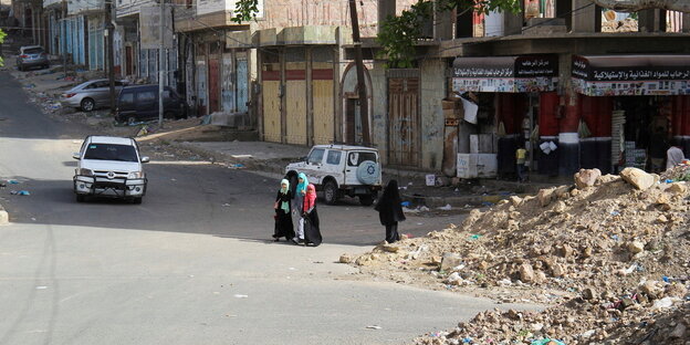 Eine Frau mit Nikab läuft mit Kindern über eine leere Straße.
