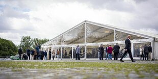 Einige Personen, vor allem Männer, unterhalten sich vor einem großen Plastik-Festzelt auf dem Schützenplatz in Hannover; die AfD Niedersachsen hat hier ihren Landesparteitag abgehalten