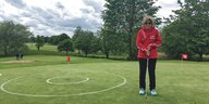 Stefanie Lutz steht auf einem Golfplatz und hat einen Golfschläger in der Hand.