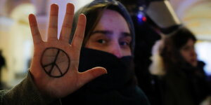 Eine Person zeigt ein Peace-Zeichen bei Protesten.