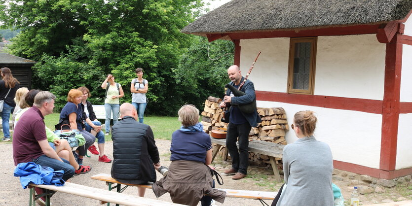 Ralf Gehler mit Dudelsack vor der Reetdach-Kate