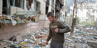 Eine Person steht vor den Trümmern eines Wohnhauses.