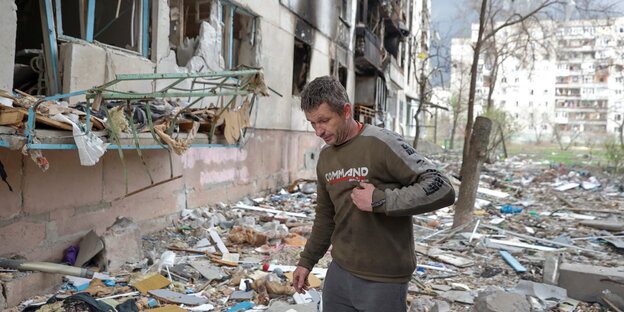 Eine Person steht vor den Trümmern eines Wohnhauses.