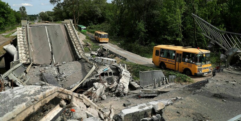 Ein gelber Bus fährt an einer zerstörten Straße entlang