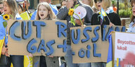 Menschen halten Protestplakate gegen den Import von russischem Öl und Gas