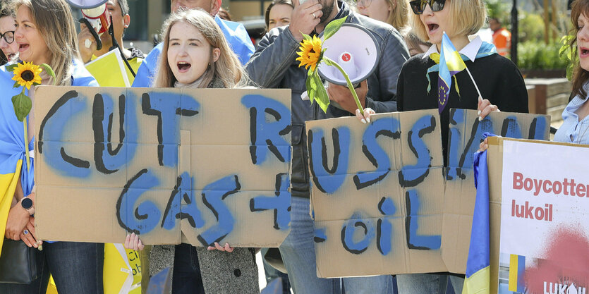 Menschen halten Protestplakate gegen den Import von russischem Öl und Gas