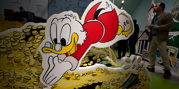 Ein Bild von Dagobert Duck, der in einen Speicher voll Gold taucht