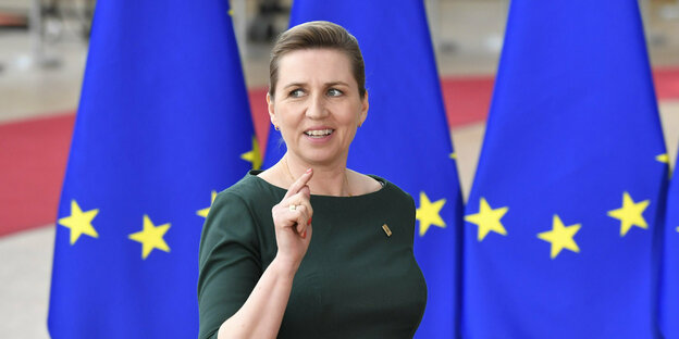 Mette Frederiksen, die Ministerpräsidentin von Dänemark, steht mit erhobenem Zeigefinger vor EU-Fahnen