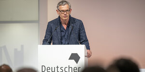 Der Historiker Stephan Malinowski steht an einem Lesepult mit der Aufschrift "Deutscher (Sachbuchpreis 2022)".