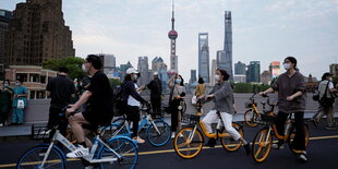 Fahradfahrer:innen vor der Kulisse Shanghais.