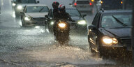 Fahrzeuge auf einer überfluteten Straße.