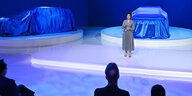 Eine Frau auf einer blau erleuchteten Bühne
