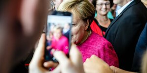 Angela Merkel wird mit einem Smartphone fotografiert.