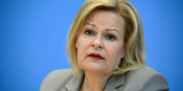 Nancy Faeser (SPD), Bundesministerin für Inneres und Heimat, bei einer Pressekonferenz. graues Sakko, blauer Hintergrund