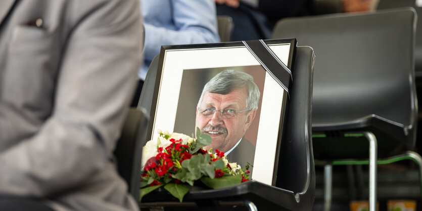 Das Foto von Walter Lübcke im schwarzen Bilderrahmen steht auf einem Stuhl, daneben liegen Blumen