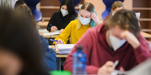 Schüler sitzen schreibend an ihren Tischen