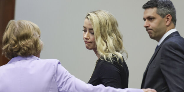 Amber Heard (M) reagiert mit ihren Anwälten Elaine Bredehoft und Benjamin Rottenborn (r) nach der Urteilsverlesung im Fairfax County Circuit Courthouse.