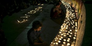 Menschen sitzen vor brennenden Kerzen