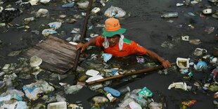 Eine Person zwischen Plastikmassen im Wasser.