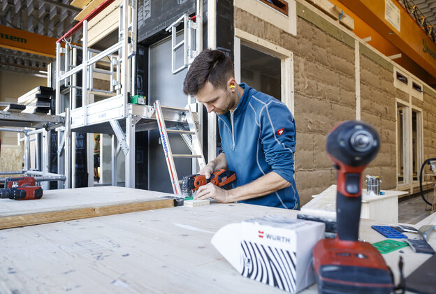 Ein Mann im Holzsystembau sägt an einer Werkbank Ein Mann im Holzsystembau sägt an einer Werkbank