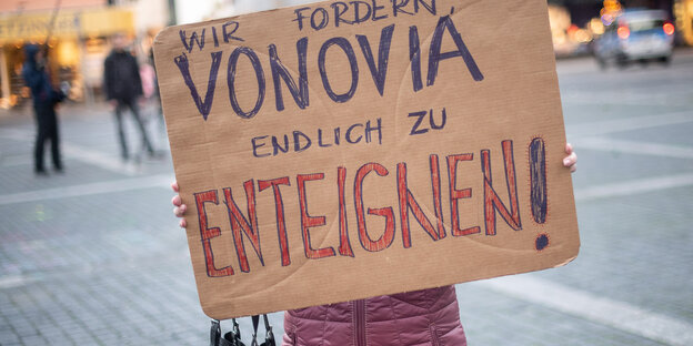 Eine Person hält ein Pappschild. Darauf: "Wir fordern Vonovia endlich zu enteignen"