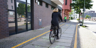 Eine Fußgängerin geht neben einem Radfahrer auf der Straße