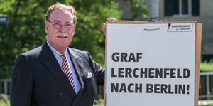 Philipp Lerchenfeld mit einem Schild mit der Aufschrift „Graf Lerchenfeld nach Berlin“