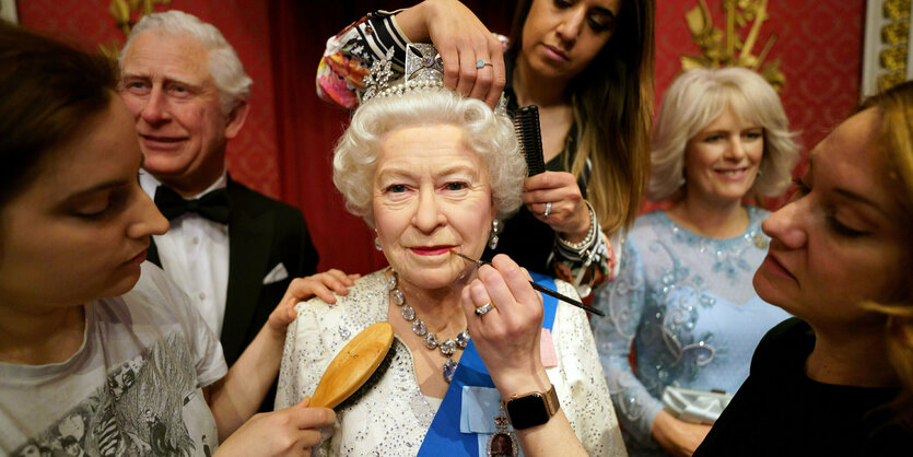 Mehrer Personen arbeiten an der Wachsfigur von Queen Elizabeth.