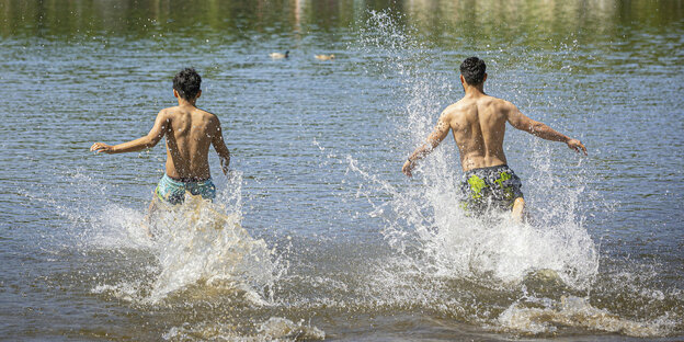 Zwei Personen renne in einen See zum Baden.