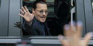 Johnny Depp grüß seine Anhänger aus einem Auto.