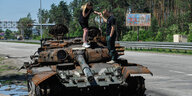 Menschen inspizieren einen zerstörten Panzer der russischen Armee