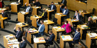 Blick auf Stuhlreihen im Thüringer Landtags in Erfurt:. Dort sitzen einige Abgeordnete. Die meisten von ihnen heben die Hand bei einer Abstimmung