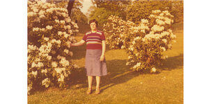 Das Foto zeigt eine Frau neben einer Hecke.