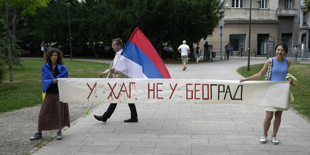 Zwei Menschen tragen ein Transparent mit kyrillischen Buchstaben