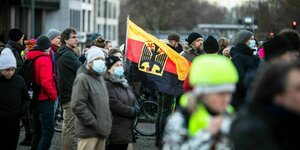 Eine Gruppe Menschen versammelt sich um eine umgedrehte Deutschlandfahne