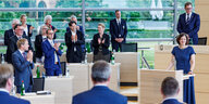 Im Kieler Landtag stehen Angeordnete hinter ihren Tischen und klatschen