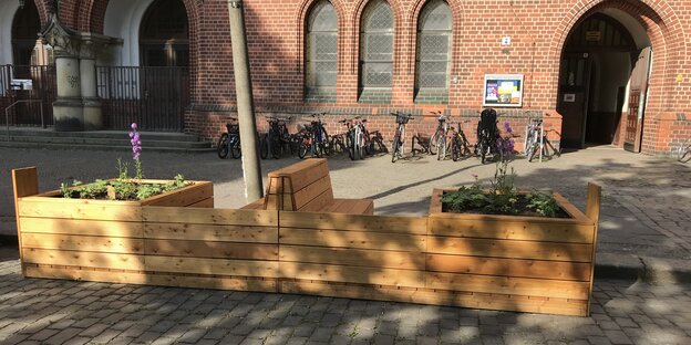 Ein Parklet vor einer Schule am Petersburger Platz in Berlin-Friedrichshain: diese hölzerne Sitzgelegenheit mit integrierten Hochbeet ist für alle da zum ausruhen etc.
