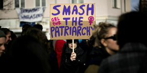 Frau hält Transparent mit der Aufschrift "Smash the Patriarchy" hoch