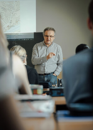 Der Lehrer Wolfgang Rall im karrierten Hemd spricht zu der Klasse Der Lehrer Wolfgang Rall im karrierten Hemd spricht zu der Klasse